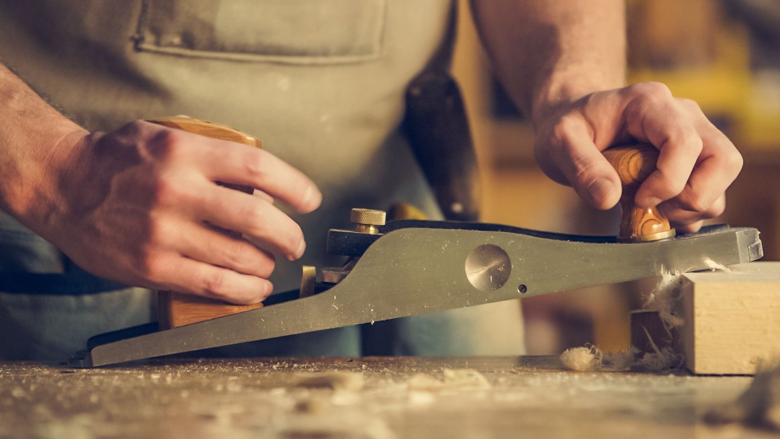 Mains d’un menuisier travaillant le bois au rabot, photographie d’illustration
